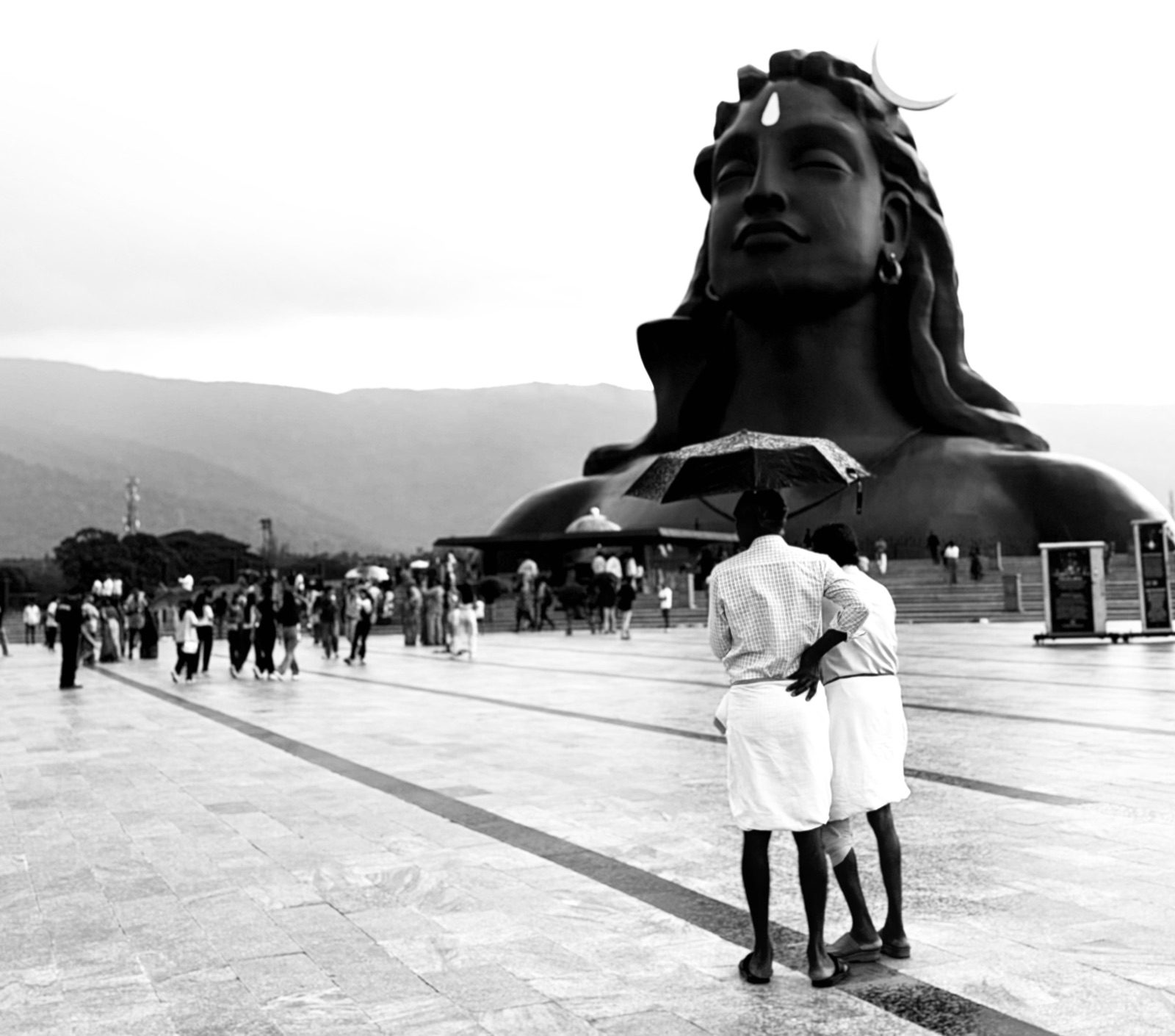 Two men under an umbrella in front of the Adiyogi statue at the Isha Foundation, Coimbatore